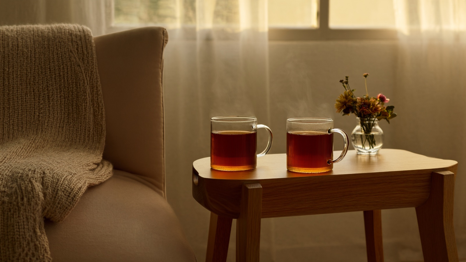 Two mugs of tea on a side table beside a soft couch in warm afternoon light, suggesting a calm and private space for conversation