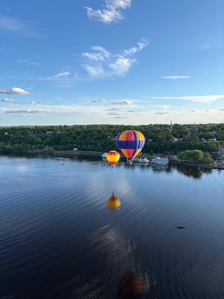 Hot air balloons drifting over the St. Croix River at Stillwater, MN, with the riverboats and downtown riverfront below